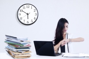 26657635 - overworked businesswoman looking at a clock. shoot at workplace