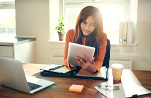 Smiling woman working with a tablet in her home office